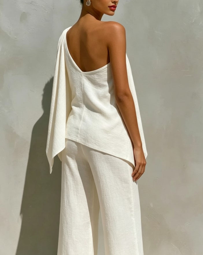 Ensemble deux pièces blanc composé d’un haut asymétrique irrégulier drapé, fendu, et d’une longue robe-pantalon à jambes larges